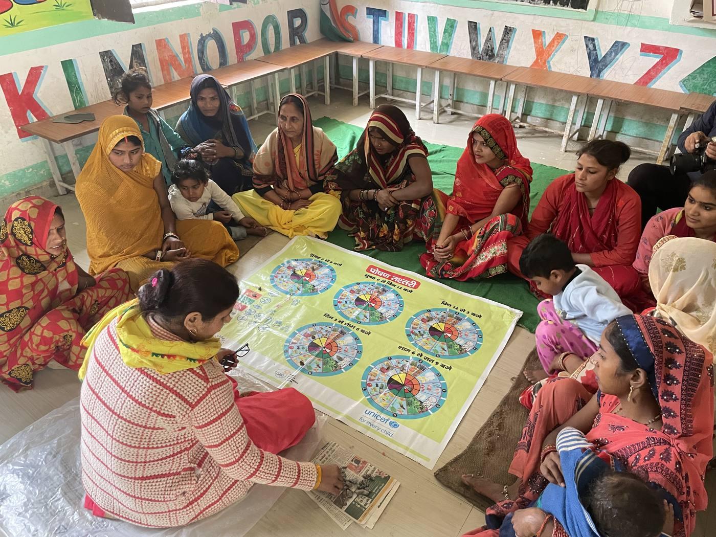 Women and children gathered around a learning game during a community session