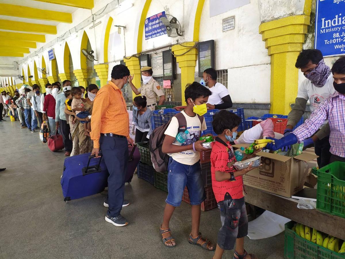 Volunteers handing out relief supplies to children and families at a railway station